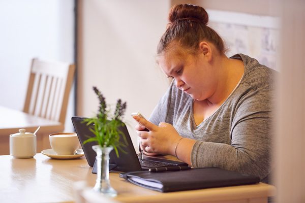 Une jeune fille obèse consulte son smartphone.